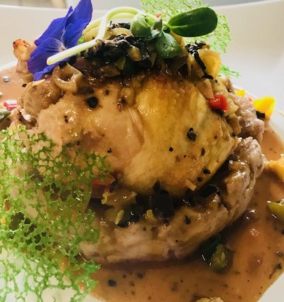 Plat chaud pintade sur un lit de légumes avec sa sauce. Elle est accompagnée de dentelle de légumes et de fleurs comestibles.